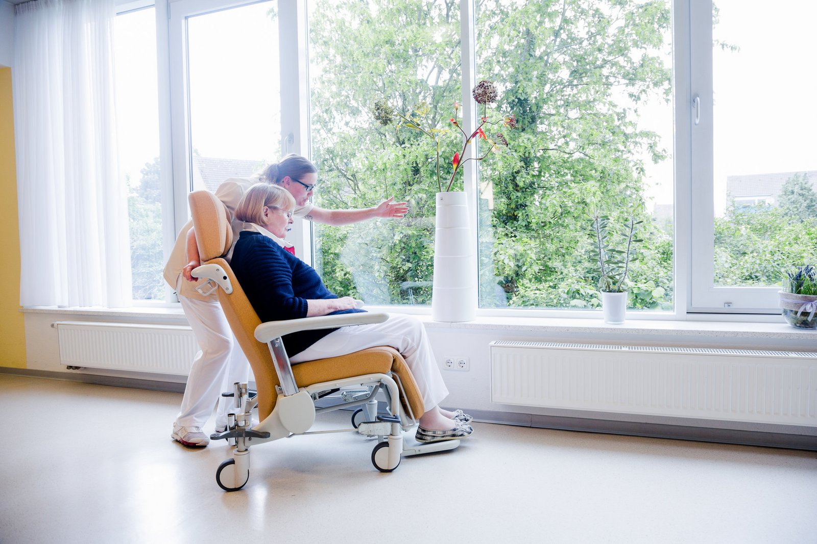 Pflegerin und Patientin im Gespräch mit Blick in den Garten Pflegerin und Patientin im Gespräch mit Blick in den Garten